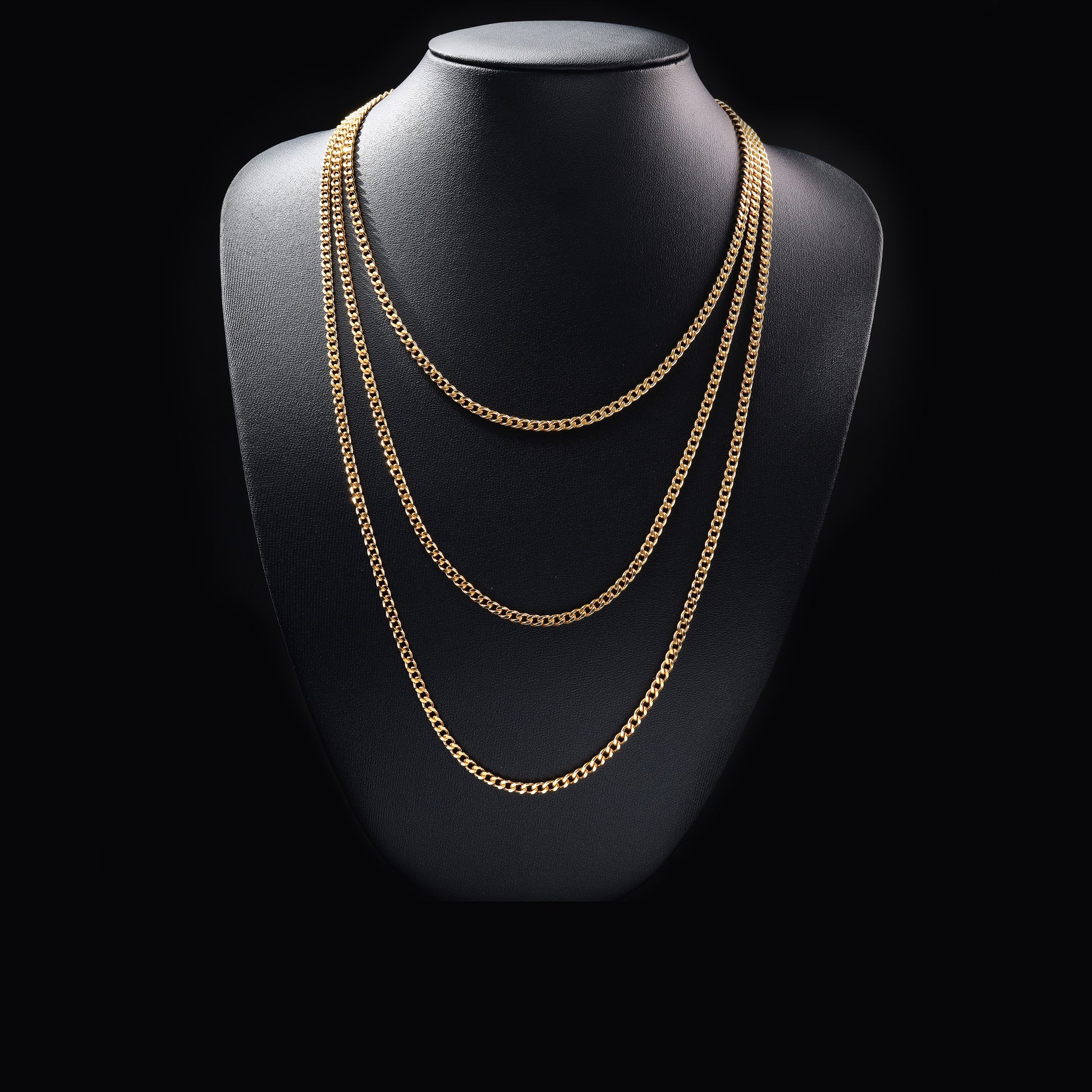 Layered gold chain necklace on black display bust