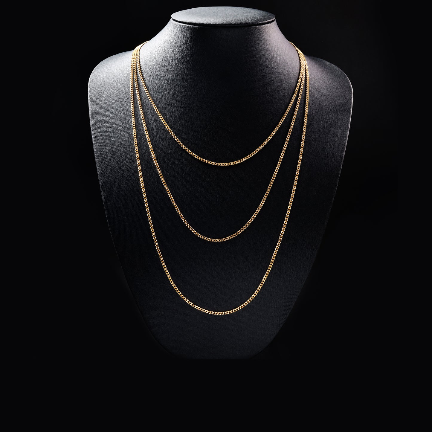 Layered gold chain necklace on black display bust