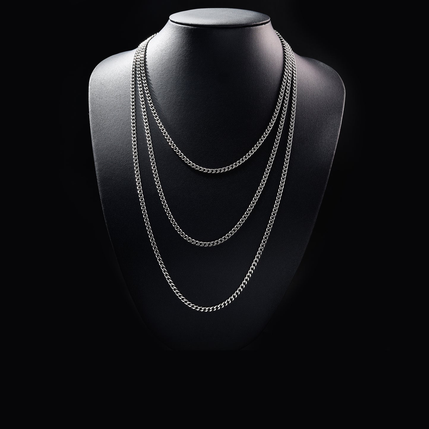 Layered silver chain necklace on black display bust