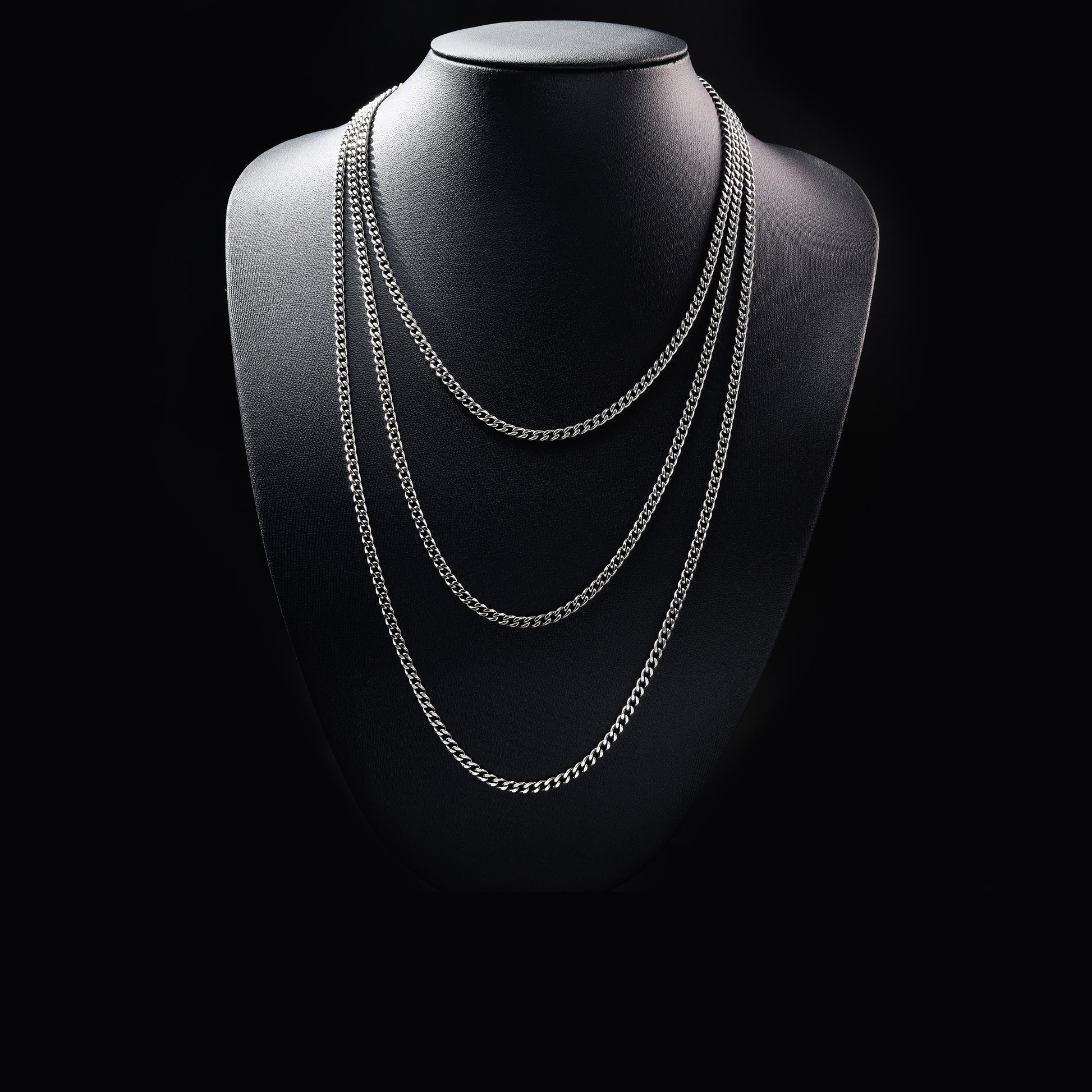Layered silver chain necklace on black display bust